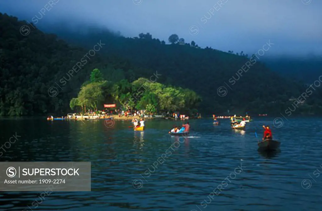 Small boats ferry Nepali worshippers to Hindu Temple at daybreak early morning sunrise on a small island in Phewa Lake at daybreak Pokhara Nepal Asia This image replaces AFK1A8