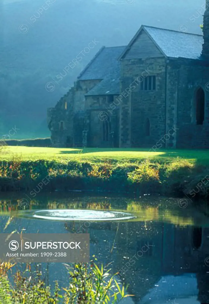 Afternoon sun shines on the ruined abbey of Valle Crucis near the Horseshoe Pass Llangollen Wales UK United Kingdom Cymru GB Great Britain Europe EU The pond was stocked with fish in monastic days as food for the monks