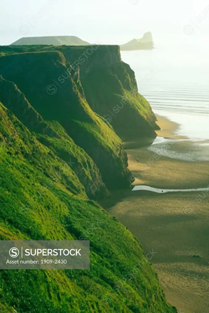 Beach and Cliffs at Rhossili Bay on the Gower Peninsula looking to Worm s Head Worms Head on a sunny summer s evening West Glamorgan Wales United Kingdom UK Great Britain GB British Isles Europe EU