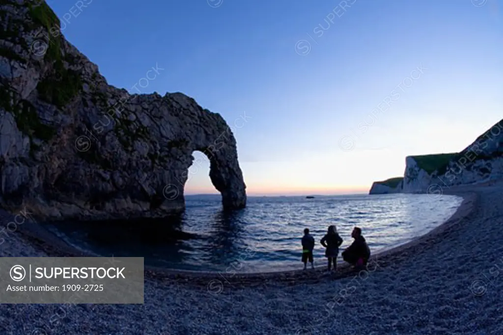Durdle Door beach with natural limestone arch UNESCO Jurassic Coast World Heritage Site on sunny summers evening with man and two young children on the beach at dusk Dorset England UK United Kingdom GB Great Britain British Isles Europe EU