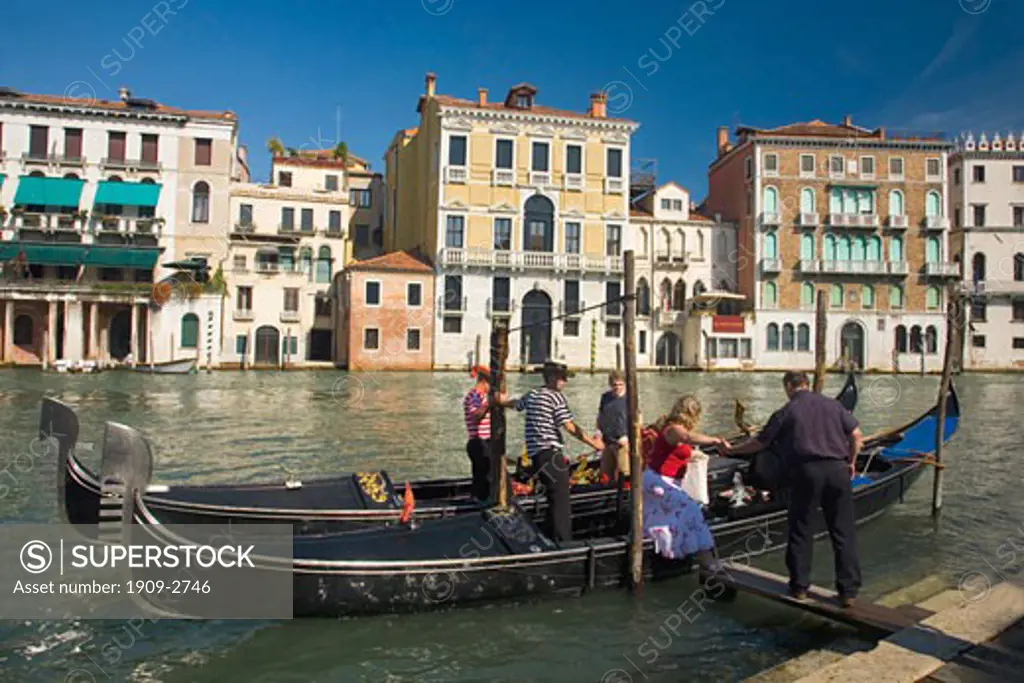 Gondolier helping tourists from gondola on the Grand Canal Venice Veneto Italy Europe EU