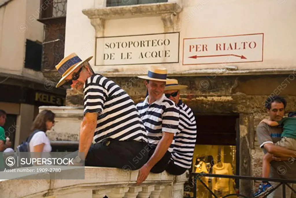 Three 3 Gondoliers in blue striped mariner shirts and straw boater hats with blue ribbons relax in side streets of Venice Veneto Italy Europe EU