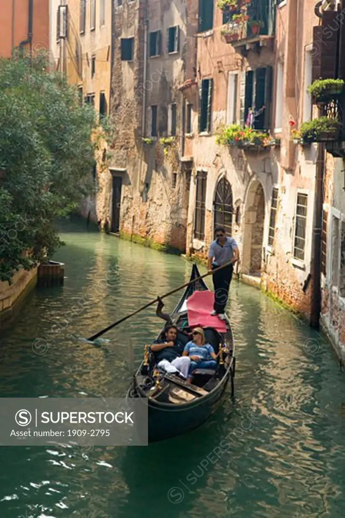 Gondolier rowing tourists around side canals in Venice Veneto Italy Europe EU