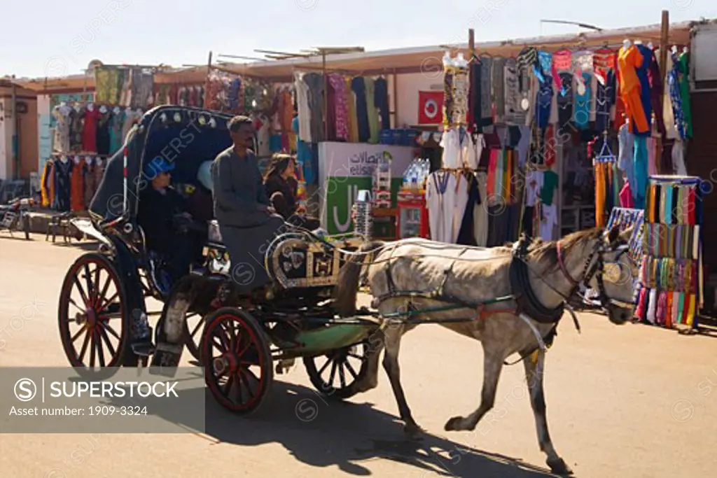 Horse drawn carriage or Hantour carries tourists past market stalls and through the streets of Edfu Egypt North Africa