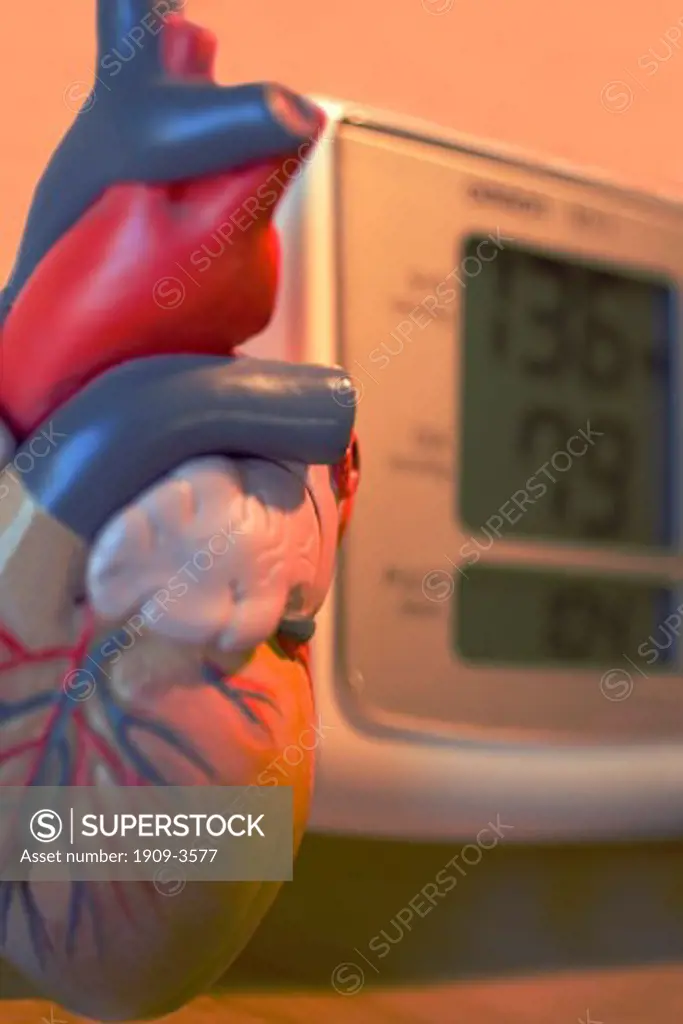 Electronic Sphygmomanometer scale and model of heart close-up close up closeup of medical instrument used by doctors to measure blood pressure BP