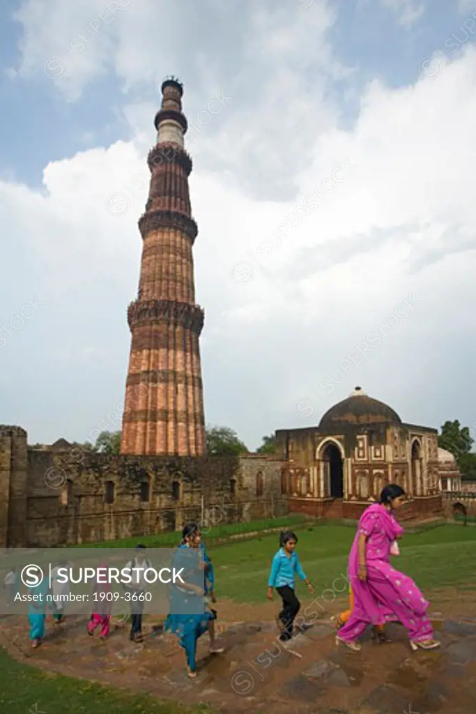 Indian family visiting the Qutub Qutb Minar Tower in Delhi is the tallest brick minaret in the world at 72 meters high built in 12th - 13th century with courtyard and carved stone pillars taken from Hindu Temple India Asia