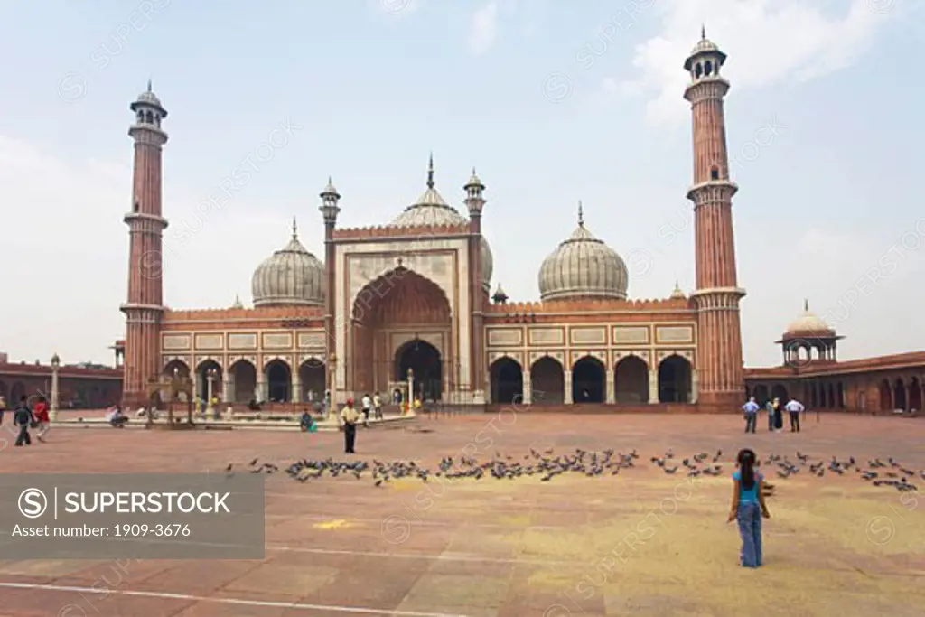 Young indian girl standing in main courtyard with minarets and domes of the Jami Masjid Mosque built in 1656 by Emperor Shah Jahan in Delhi Uttar Pradesh Northern India Asia