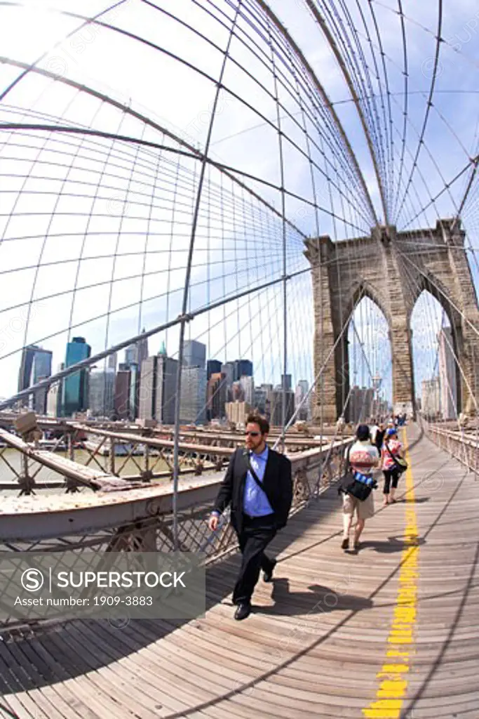 Tourists and New Yorkers pedestrians enjoy walking in sunshine on Brooklyn Bridge Lower Manhattan New York City NYC USA United States of America North This image replaces ABNM0K