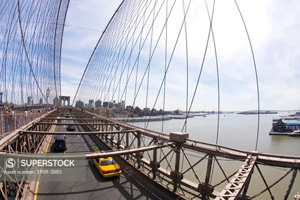 Brooklyn Bridge in spring sun sunshine with yellow taxi cab on road Lower Manhattan New York City NYC USA United States of America North