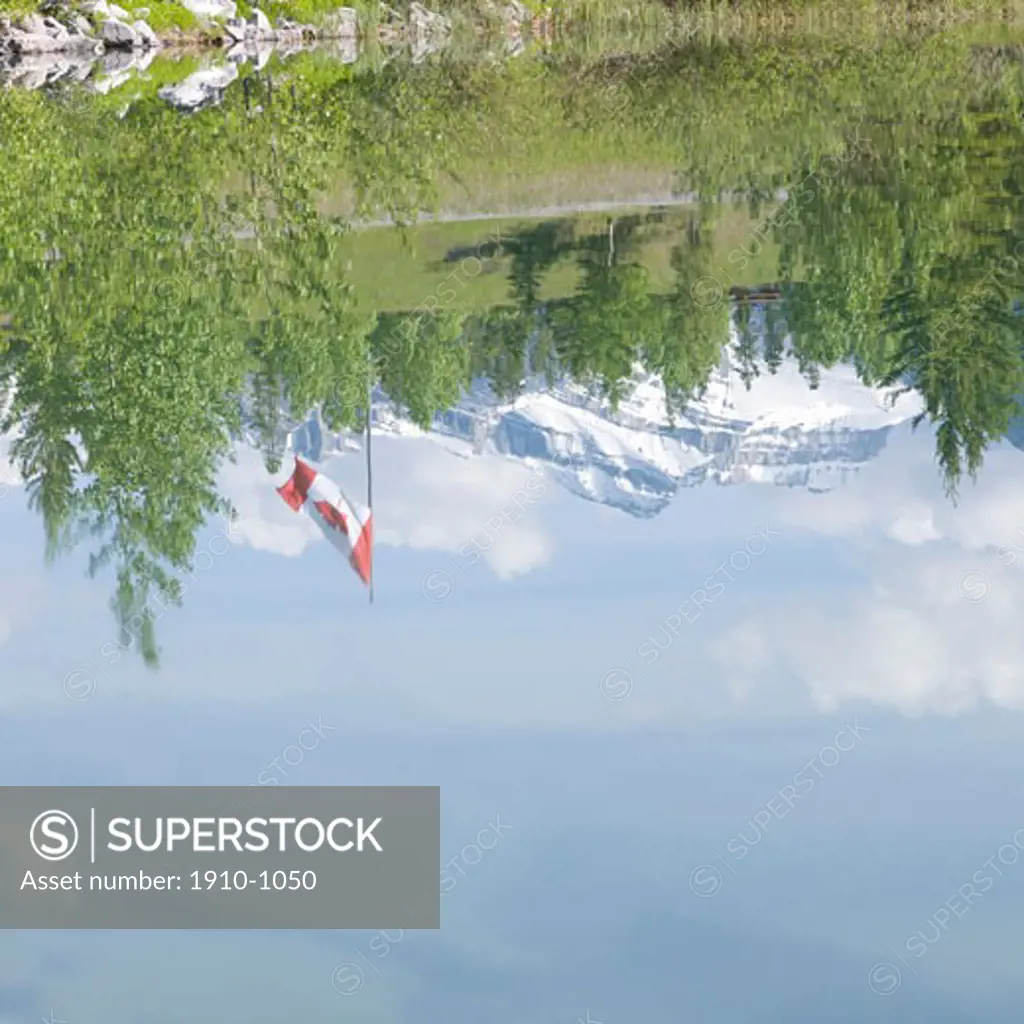 Mountains and Canadian flag reflected in Quarry Lake  near Canmore  Canada  Alberta