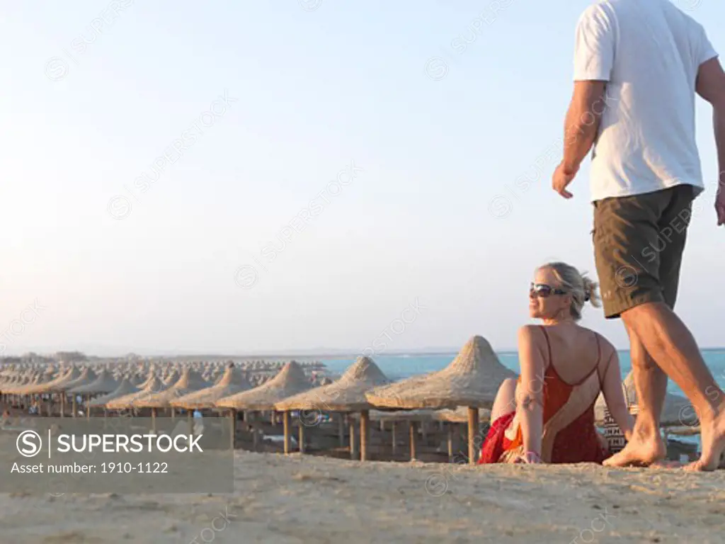 Man joins woman on sandy pow above beach palapas  Sahara Desert and Red Sea in distance  Egypt  Red Sea Riviera  Marsa Alam