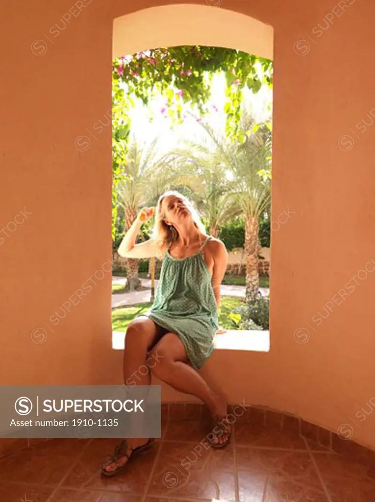 Mother brushes her hair in the window sill of hotel lobby  Egypt  Red Sea Riviera  Marsa Alam