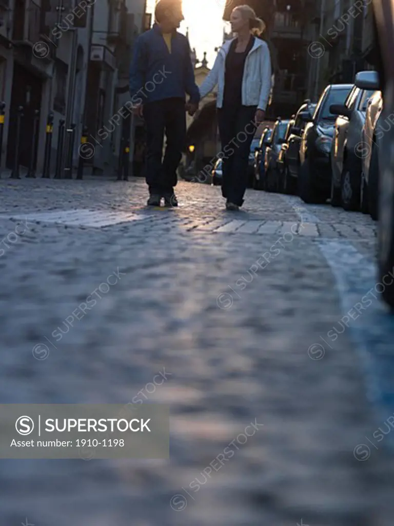Couple walk together on cobblestone street  low perspective  Italy  Piedmont