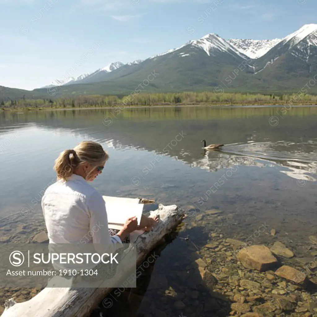 Woman sketching with passing Canada goose Branta canadensis at Vermillion Lake near Banff townsite The chain of 3 beautiful Vermillion Lakes can easily be reached on foot from the town CANADA Alberta