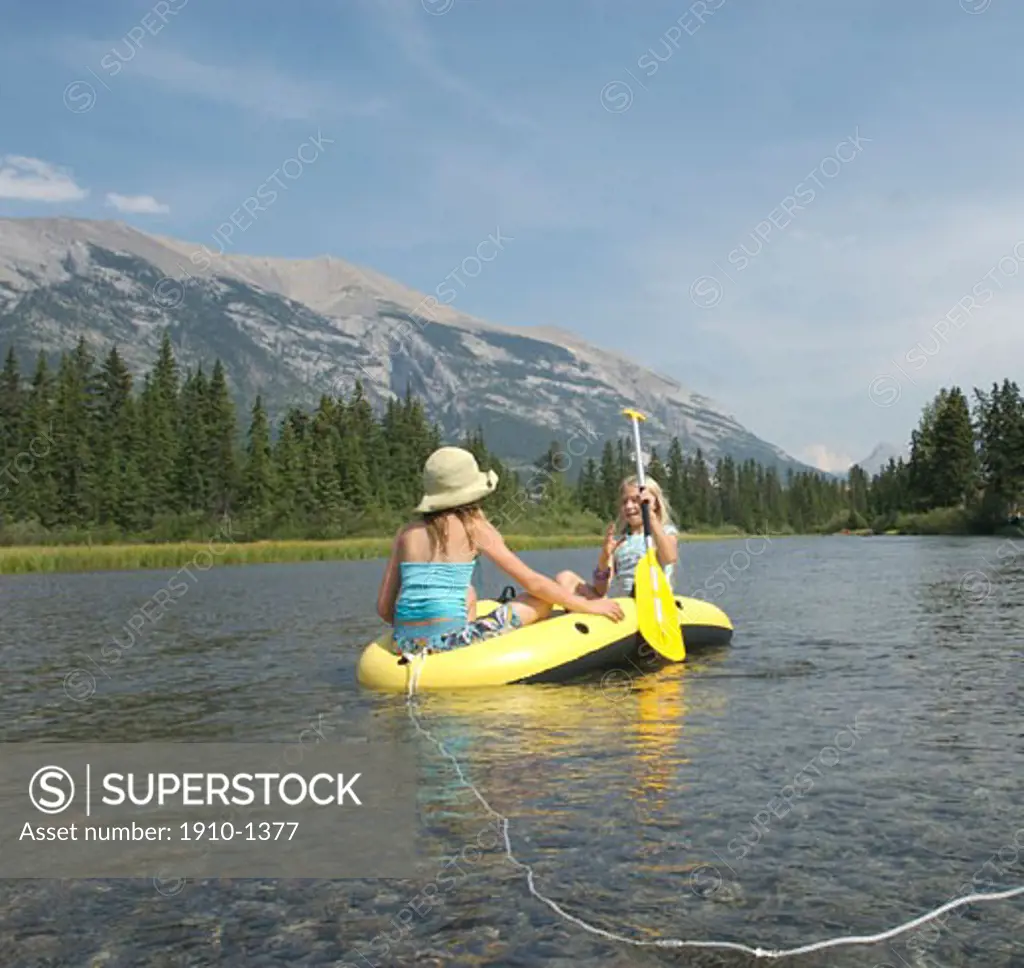 Girls 10-11 yrs drifting down creek in inflatable raft Canmore CANADA Alberta