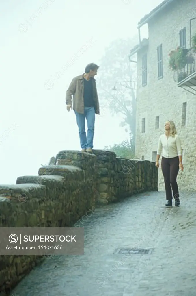 Couple walking through fog on medieval streets village in Marche ITALY Marches