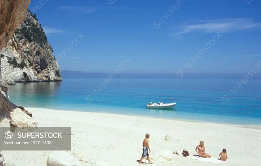 Family enjoying beach with inflatable boat used for access parked just offshore near Cala Ganone The Gulf of Orosei is behind a Marine oasis inside the Gennargentu National Park known world-wide for its limestone cliffs ITALY Sardinia