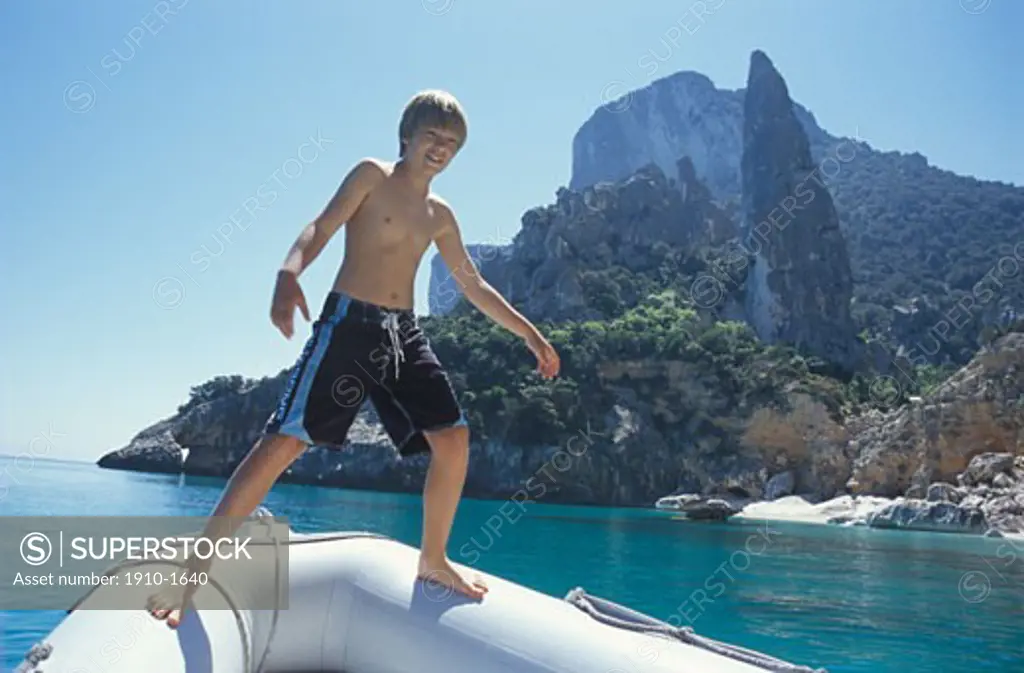 Boy 12 balancing on sides of inflatble boat while daugher looks on near Cala Ganone Sardinia This area is part of the Gulf of Orosei a Marine oasis inside the Gennargentu National Park known world-wide for its limestone cliffs ITALY Sardinia