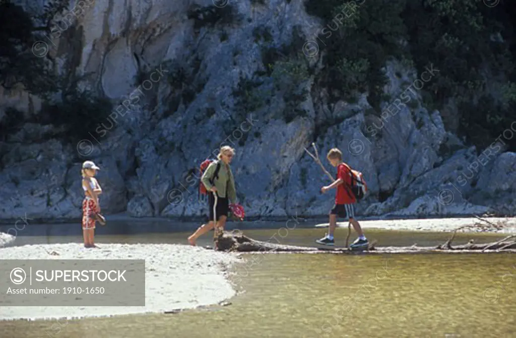 Family crossing stream in estuary area in the Gennargentu National Park near Cala Ganone known world-wide for its limestone cliffs ITALY Sardinia