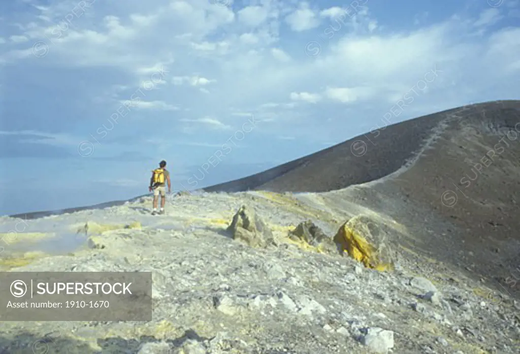 Man walking along ridgecrest of steaming volcanic activity Vulcano is apart from Stromboli the Eolian island with the most recent volcanic activity eruption of 1888-1890 It offers the most spectacular crater and fumaroles ITALY Aeolian Islands Vulcano