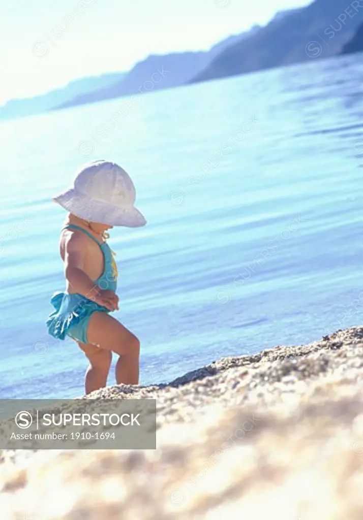 Young girl 1 - 2 yrs walking along sand beach near Loreto about halway down the Baja peninsula MEXICO Baja California