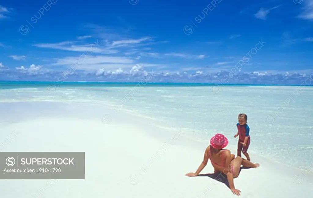 Woman and daughter playing relaxing on perfect white sand beach  coral atoll TAHITI French Polynesia Moorea