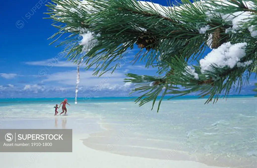 Woman and daughter playing on perfect white sand beach Pine bough with dripping icicle in foreground digital composite  TAHITI French Polynesia Moorea