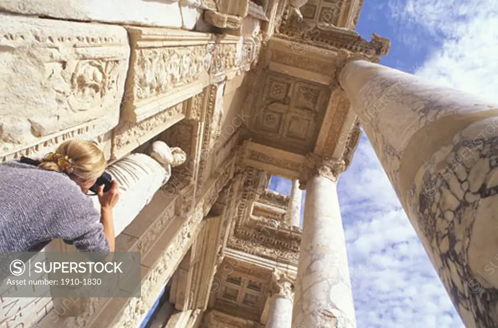 Woman taking upwards photograph of pillars at entrance to Library of Celcus Ephesus TURKEY Ephesus