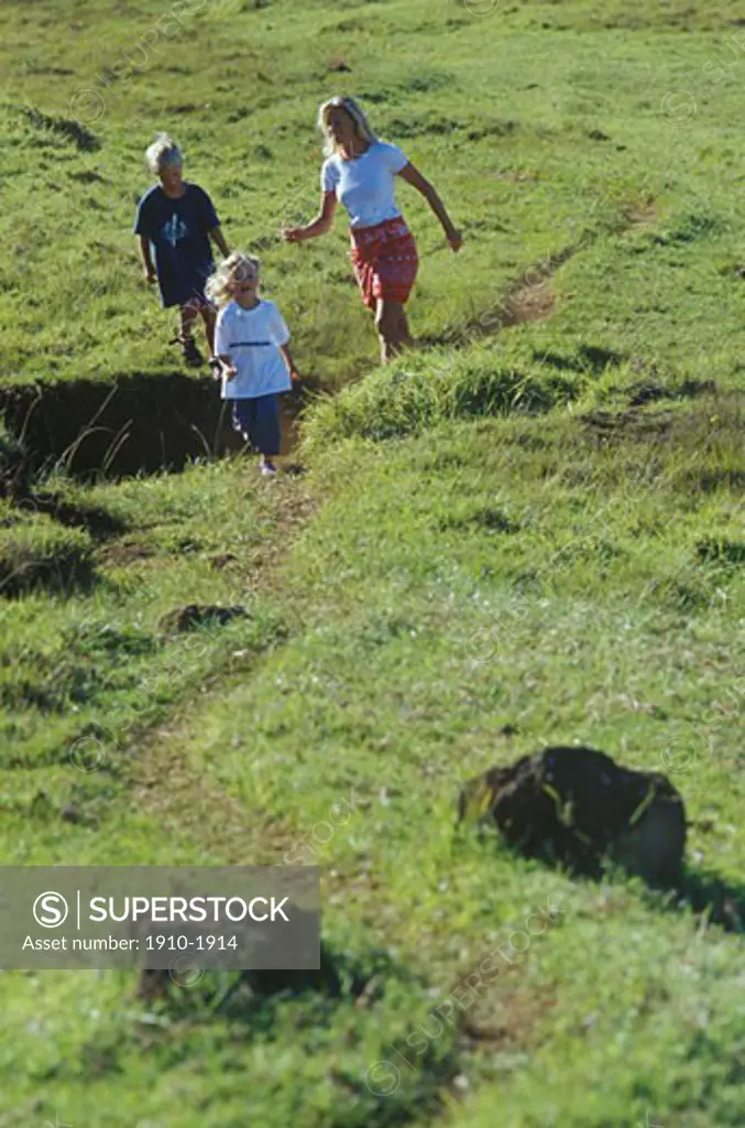 Family running down grass trail below Haleakala Volcano Haleakala Natl Park USA Hawaii Maui