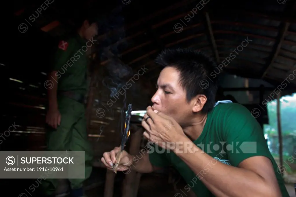 A KIA's soldier light a cigarette with a fire wood in Naw HPyu Post in the front line of the war against the Burma Government, Myanmar on August 2, 2012.