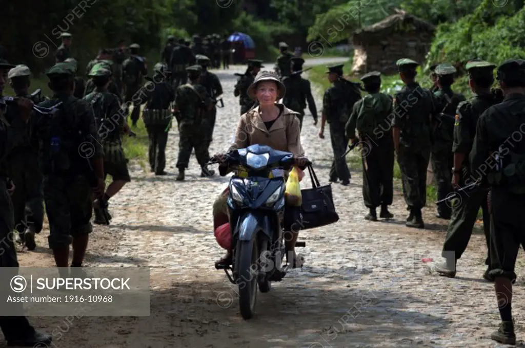 A Kachin woman pass through a KIA's battalion with her moped while they come back to Laiza from the front line, Kachin State, Myanmar on August 8, 2012.