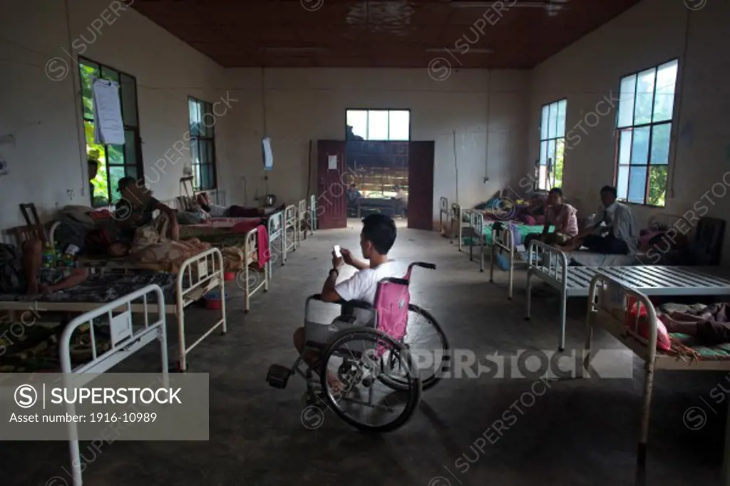 Kachin's militia member Lalaw Ze Dai, from Waimaw village, 25, play with his phone in the General Military Hospital in Laiza village close to the China border, Myanmar on July 19, 2012.  He was injured by a landmine in June, 26, 2012 loosing part of his right leg on top of knee.