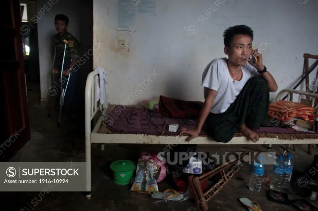 Kachin's militia member Lalaw Ze Dai, from Waimaw village, 25, smoke and  talk on the phone in the General Military Hospital in Laiza village close to the China border, Myanmar on July 26, 2012. He was injured by a landmine in June, 26, 2012 loosing part of his right leg on top of knee.