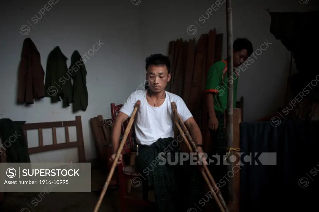 Kachin's militia member Lalaw Ze Dai, from Waimaw village, 25, try to stand up with his crutches in the General Military Hospital in Laiza village close to the China border, Myanmar on July 26, 2012. He was injured by a landmine in June, 26, 2012 loosing part of his right leg on top of knee.