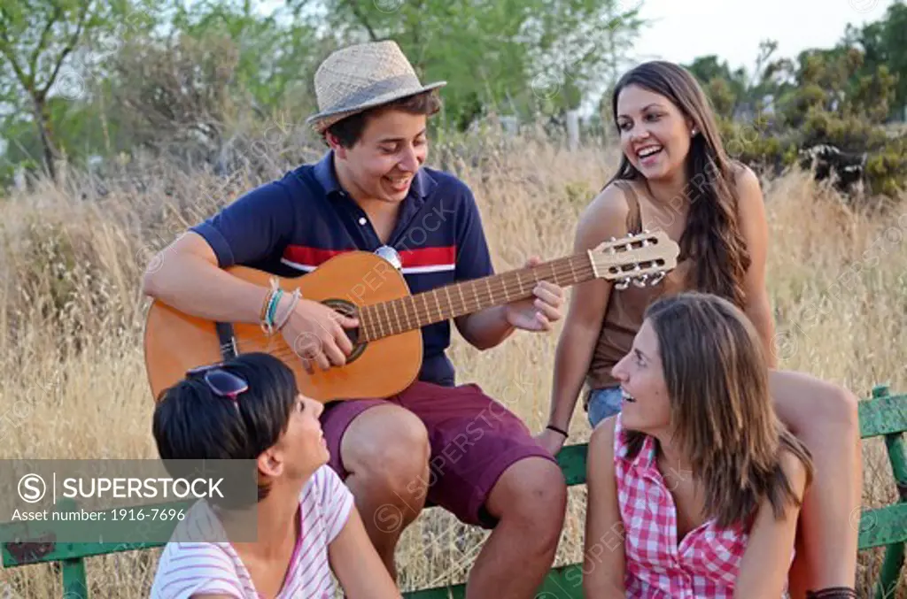 Young man plays Spanish guitar for her three friends