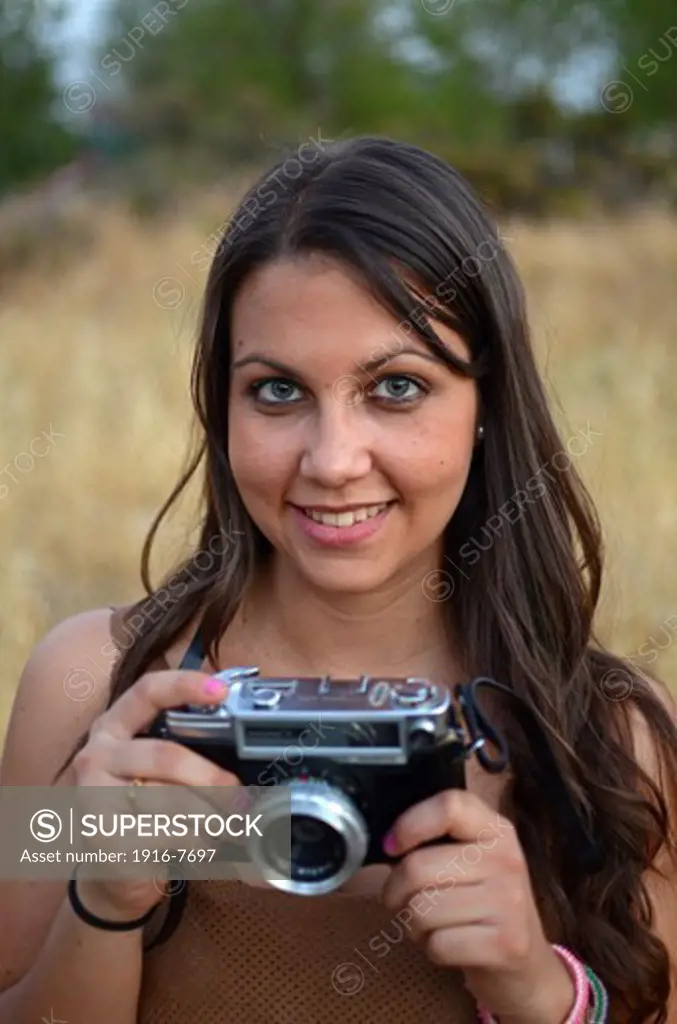Cute young woman using  old camera