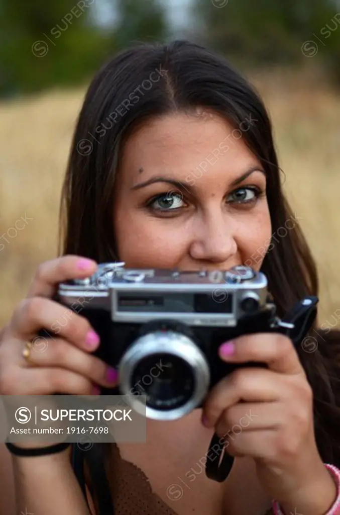 Cute young woman using  old camera