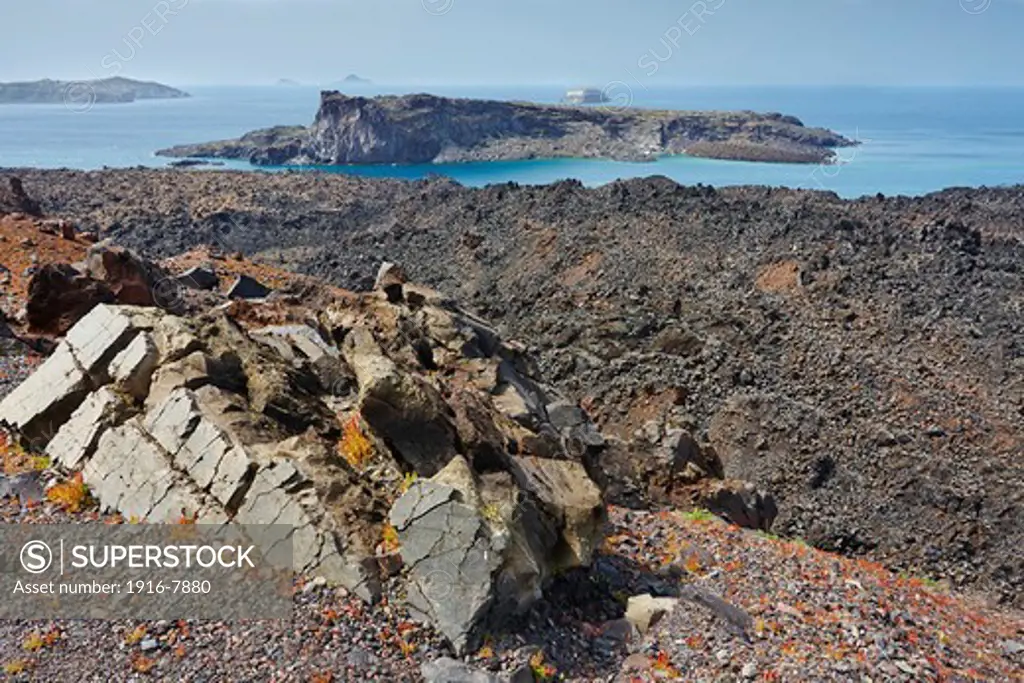 Lava and volcanic rocks with Palea Kameni and Aspronisi islands in the background from Nea Kameni Island, Santorini, Greece