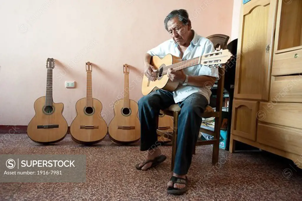 Peru, Ayacucho, handicraft. Honorato Ramos luthier specializing in ayacuchan classic guitar , testing his latest creations.