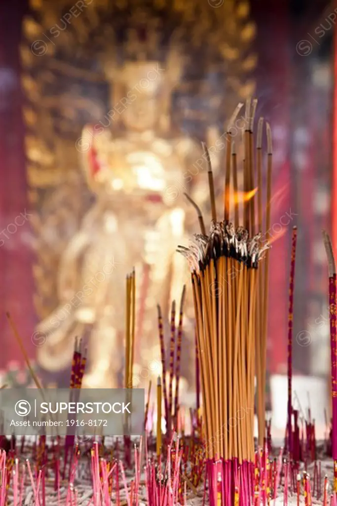 Incense bars burning in front a buddha. Temple of International Buddhist Society. Richmond, British Columbia, Canada