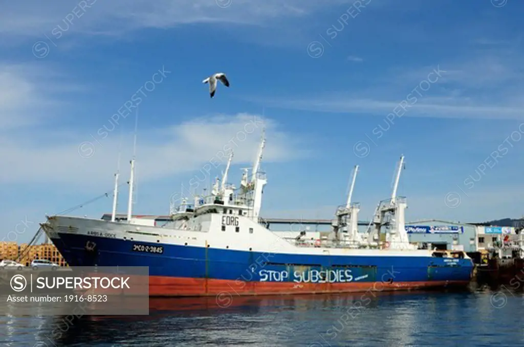 Fishing ships tied to the docks with an environmental graffiti on the hull. Vigo, Galicia, Spain