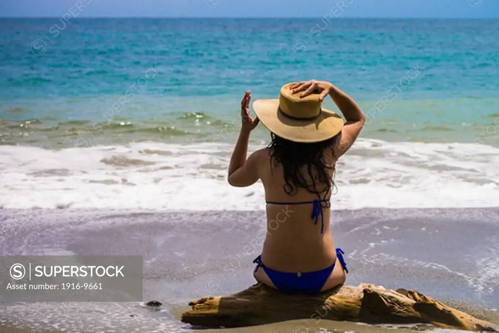 Young latin woman in bikini with a straw hat on the beach, Gorgona island