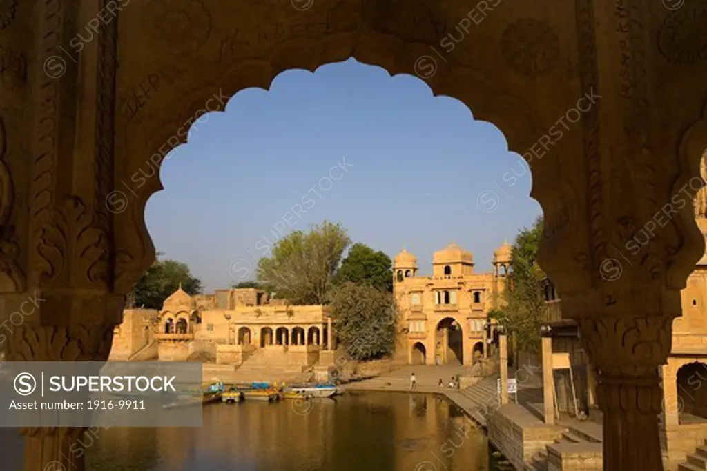 Gadi Sagar, the tank was once the water supply of the city and is surrounded by small temples and shrines,in background at right  Tilon ki Pol archway,Jaisalmer,Rajasthan, India