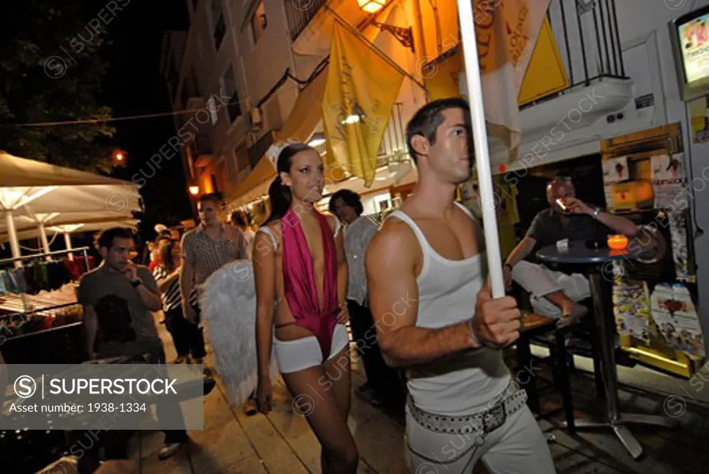Young people in the Marina port area of Ibiza  where many bars open until its time to go to the clubs and party promotional parades attract people s attention Ibiza  Spain