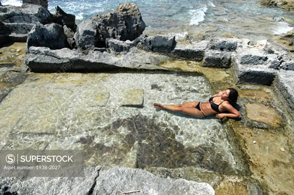 Mixed race young woman half asian half spanish relaxed in a nature made pool in Ibiza Spain
