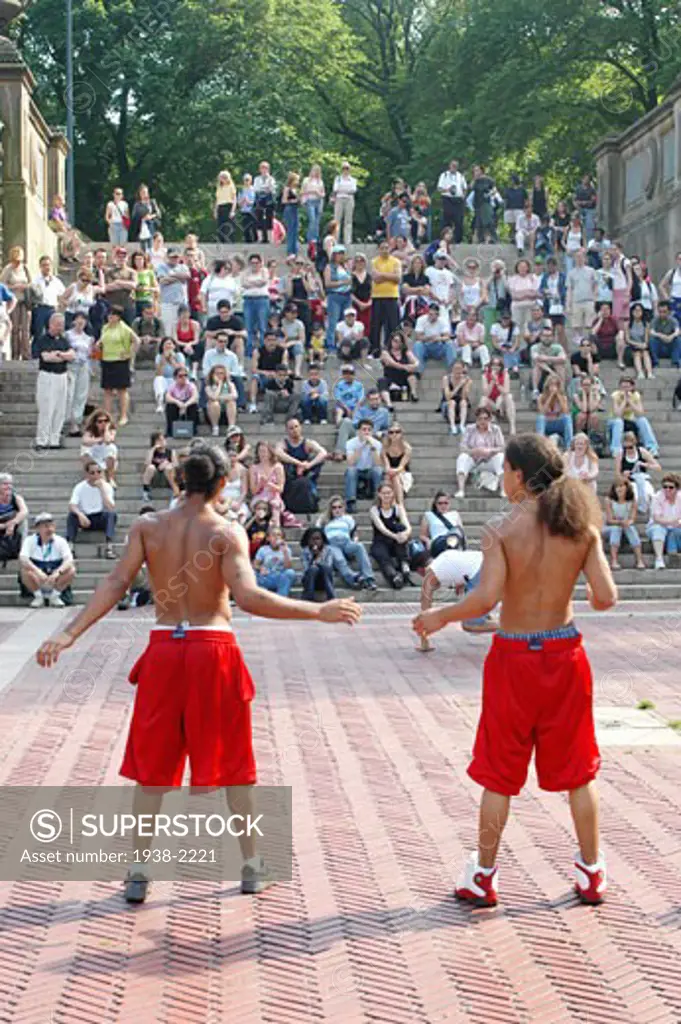 Two young men doing an acrobatics spectacle in front of an improvised audience  in Central Park  New York