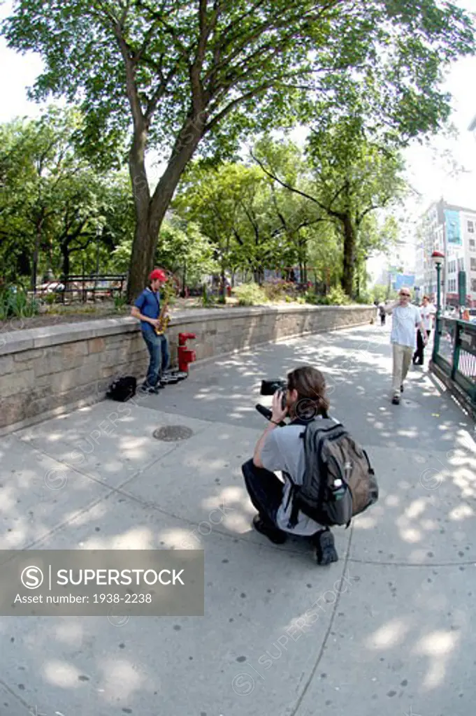 Young cameraman filming a street musician  Manhattan  NYC