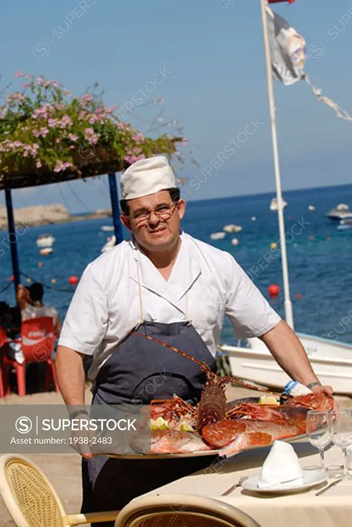 Cook posing with a tray full of fresh crayfish Port Balansat Ibiza Spain