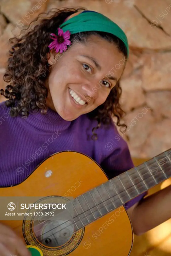 Spain, Balearic Islands, Ibiza, Portrait of young woman playing acoustic guitar