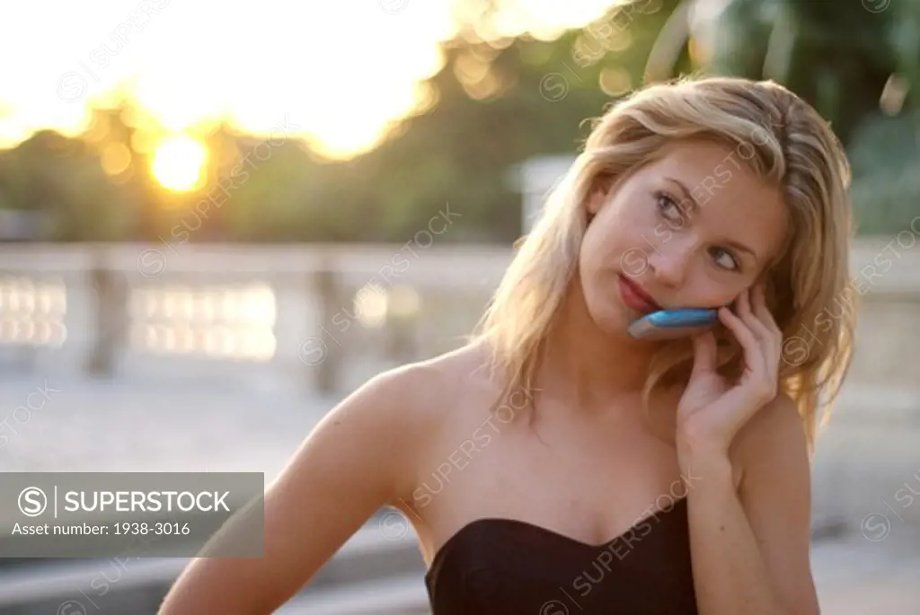 Spain, Madrid, Outdoor portrait of young blonde woman wearing elegant black dress and talking on mobile phone